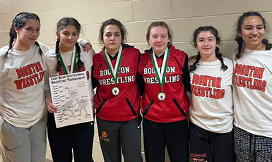  Girls holding certificates from wrestling wins.